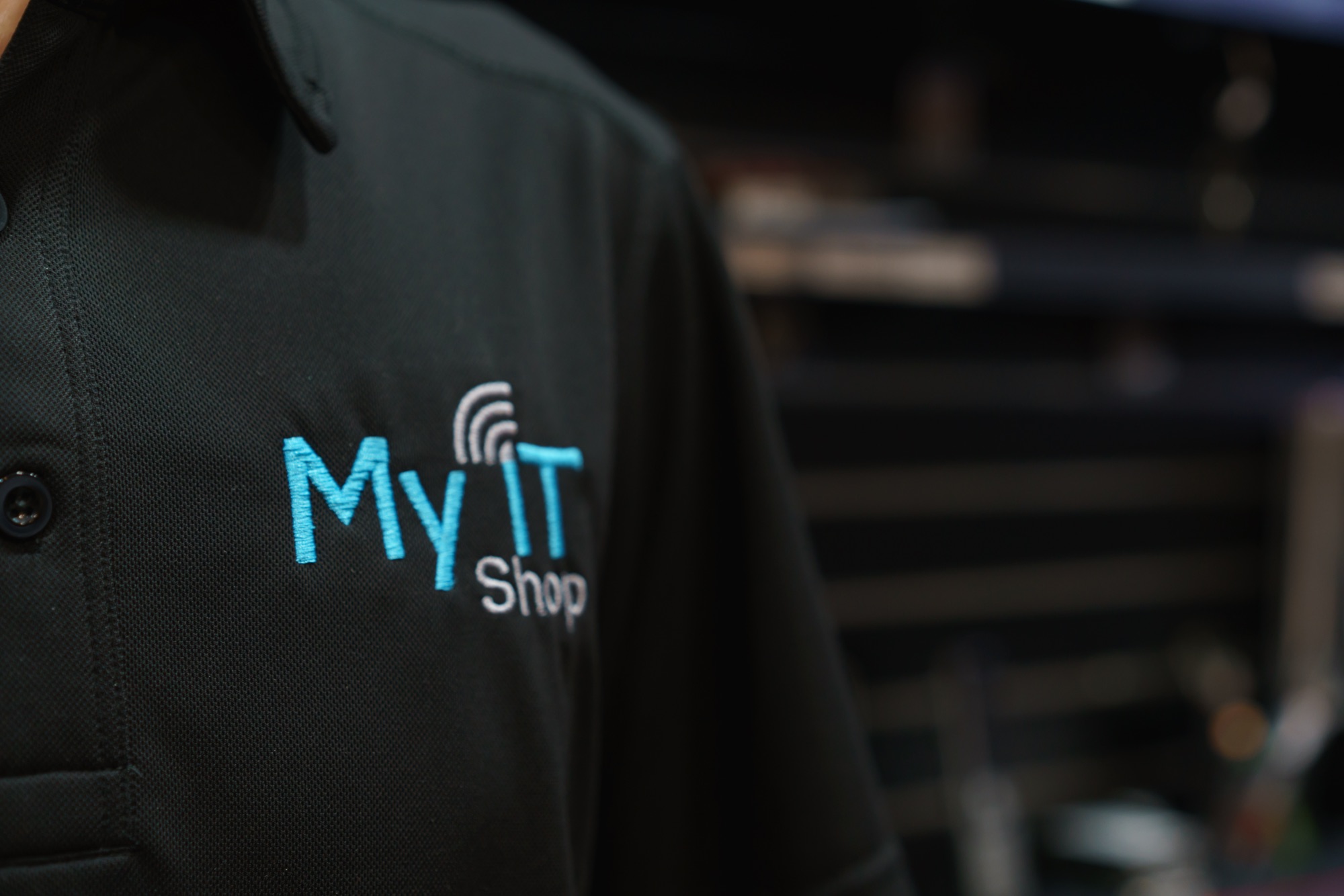 Close-up of the My IT Shop logo embroidered on a staff polo shirt